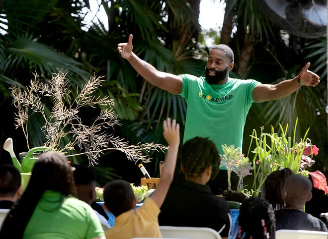 Community leader speaks to children during an Earth Day event at Ann Norton Sculpture Gardens, engaging them in a discussion about plants and healthy living.