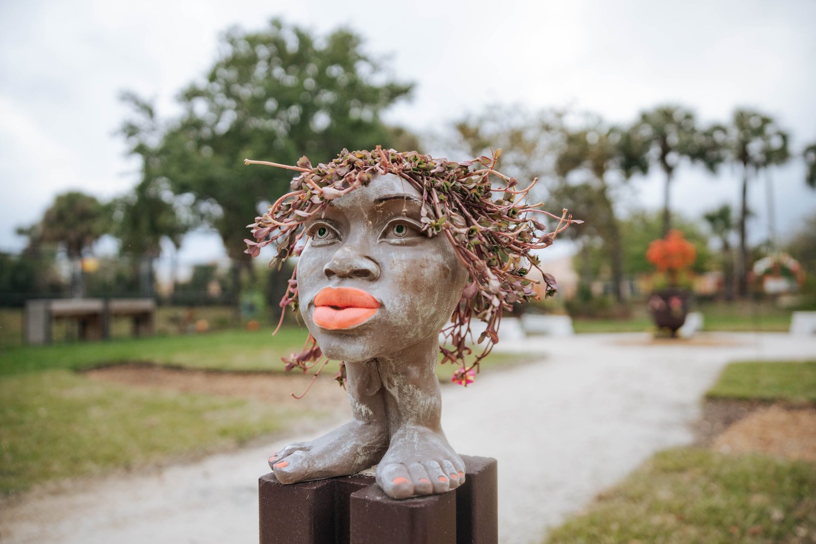 Handcrafted sculpture of a face with plant-like hair in a community garden